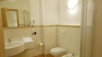 A bathroom with a sink, toilet, bidet, and a glass shower enclosure.