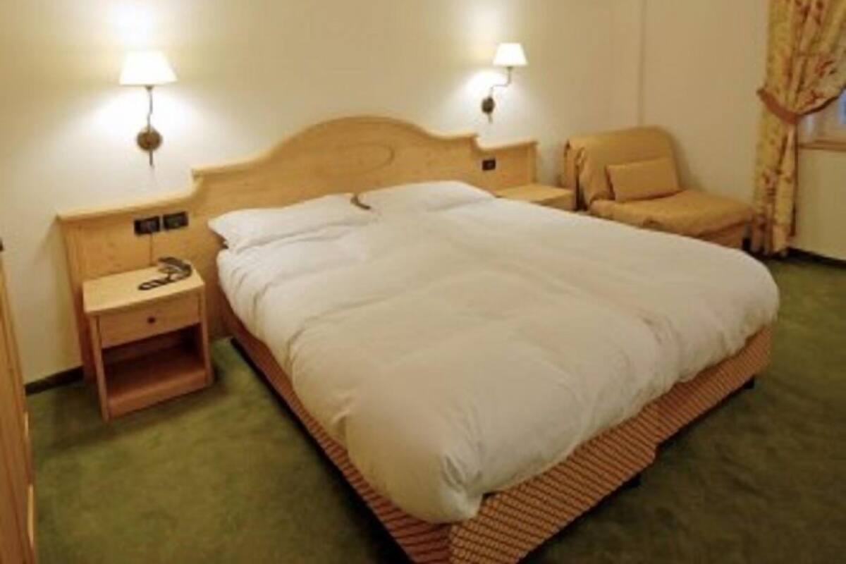 Un dormitorio con una cama grande, dos mesitas de noche con lámparas, un cabecero de madera y una alfombra verde.