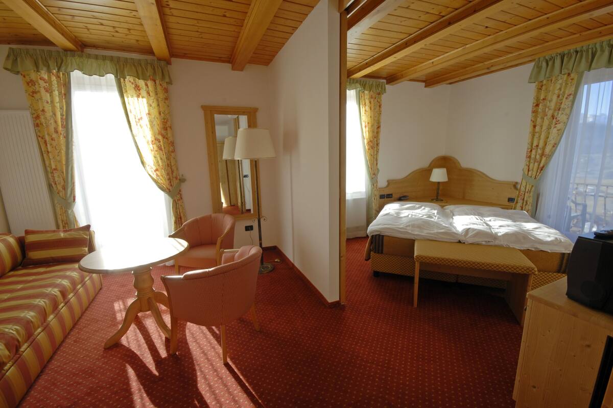 Una habitación de hotel con cama, sofá, mesa y sillón.