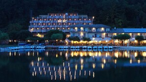 Ein Hotel am Seeufer mit mehreren Gebäuden, Außenbereichen zum Sitzen und einem Spiegelbild im Wasser.