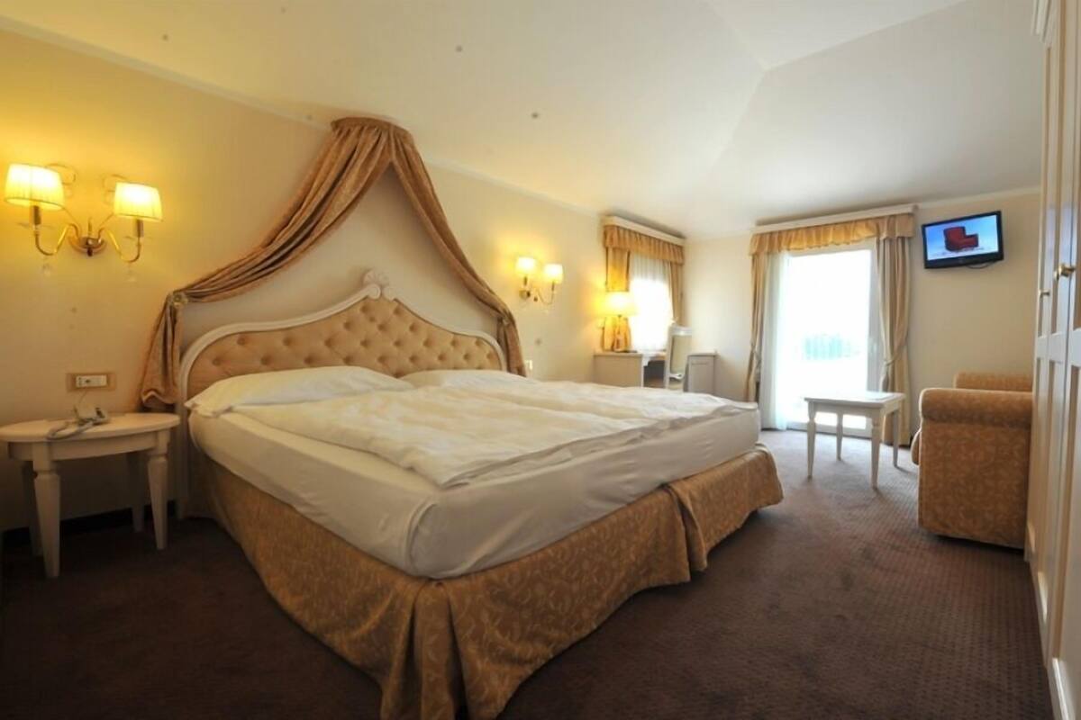 A hotel room with a large bed, bedside lamps, a television, and a small table.