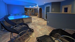 A spa area with a stone floor, a heated tub, and several massage chairs. - Hotel Arnica (Pinzolo)