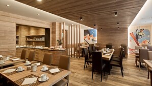 A restaurant with wooden interior, multiple dining tables, and chairs. - Hotel Arnica (Pinzolo)