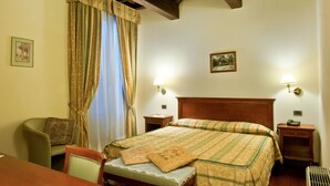 Una habitación de hotel con una cama, una silla, una mesita de noche y una lámpara.