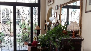 Un salón espacioso con un gran ventanal arqueado, un tapete estampado, un sofá marrón y un mueble con adornos.