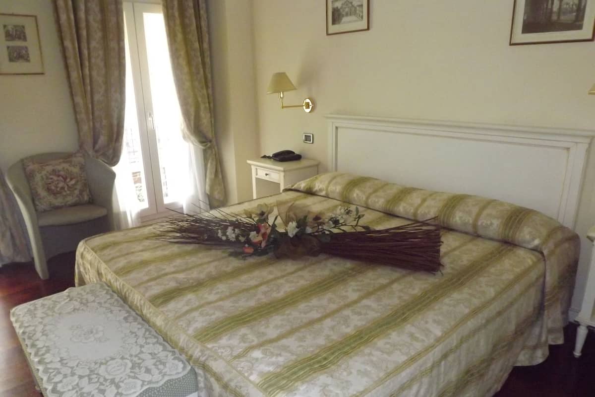A neatly arranged bedroom with a bed, a bedside table, a chair, and a window with curtains.