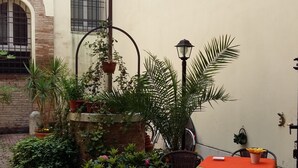Un patio con una mesa, sillas, plantas en macetas y un farol.