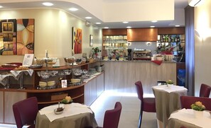 A restaurant with a bar area, buffet with various food items, and seating with tables and chairs. - Hotel Arcobaleno (Vimodrone)