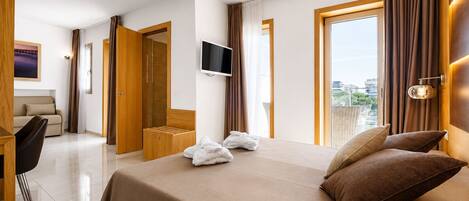 A hotel room with a bed, a TV, a desk, and a view of the city.