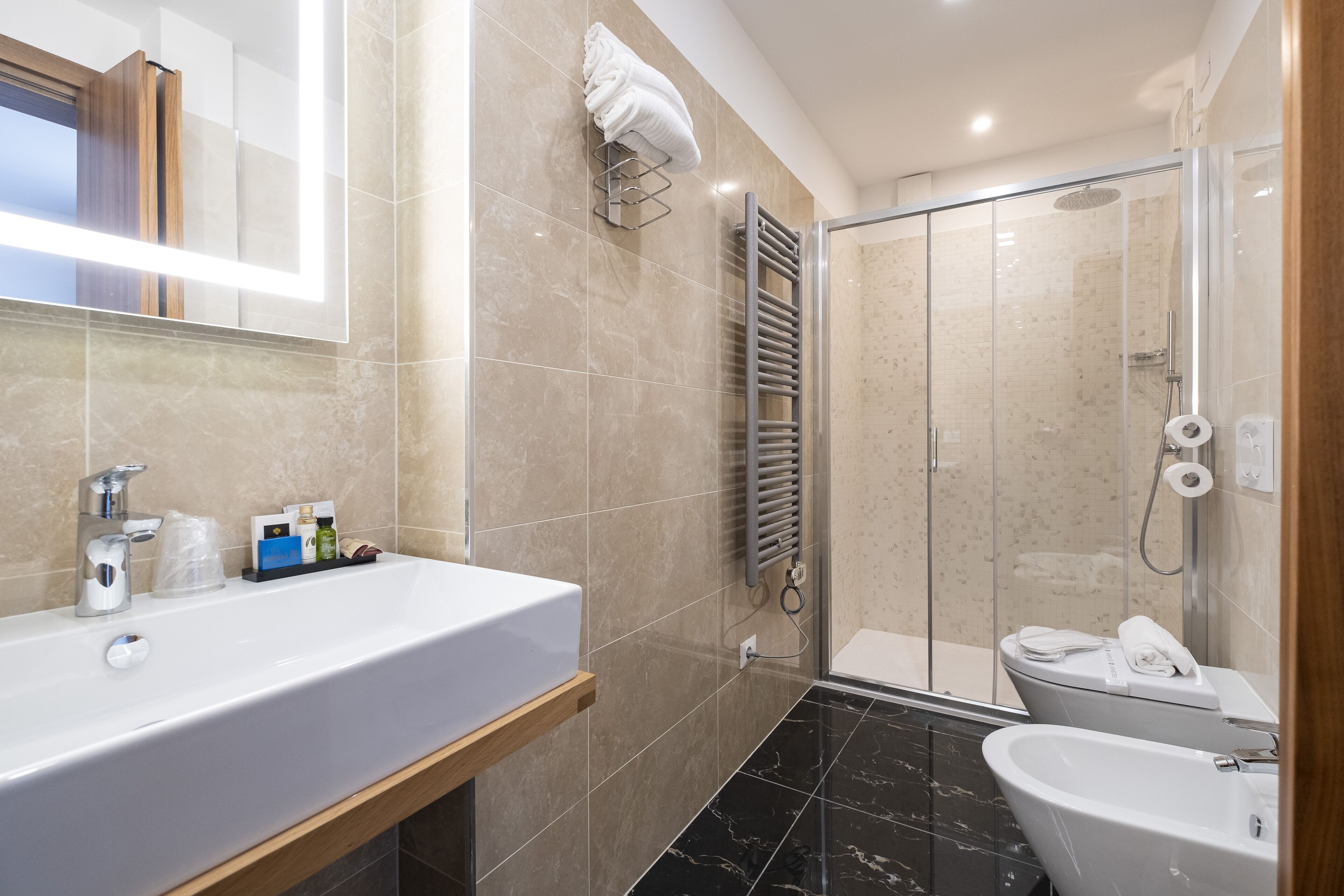 Un baño moderno con un lavamanos grande de color blanco, un box de ducha de vidrio y una bañera independiente.