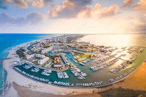Una vista aerea di una città costiera con un porto turistico, edifici e una spiaggia.