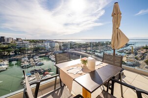 Un balcone con un tavolo apparecchiato per mangiare, con vista su una marina piena di barche e un ponte.