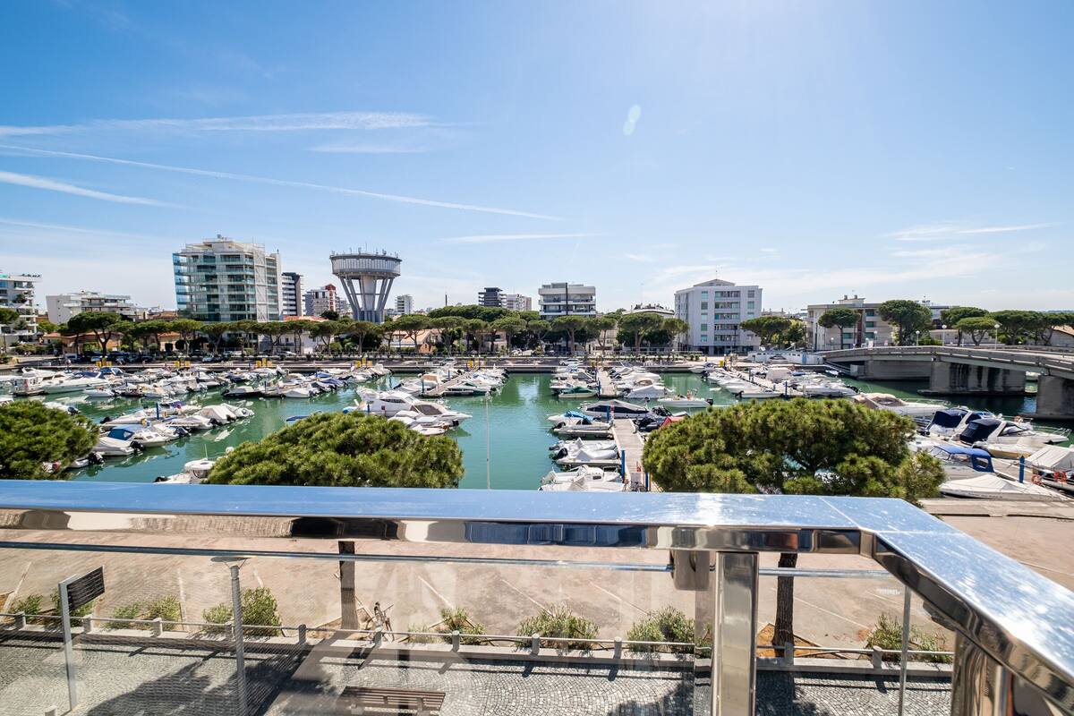 A marina with numerous boats docked, surrounded by buildings and trees.