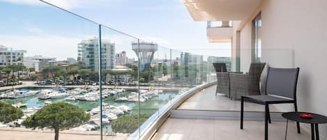 A balcony with a view of a marina, modern buildings, and a tower structure.