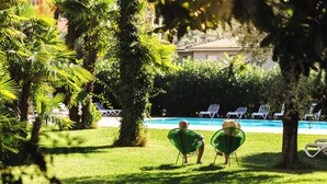 A poolside area with chairs and a pool. - Hotel Brione Green Resort (Riva del Garda)