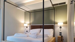 A modern bedroom with a wooden platform bed, white linens, and two bedside lamps. - Hotel Brione Green Resort (Riva del Garda)