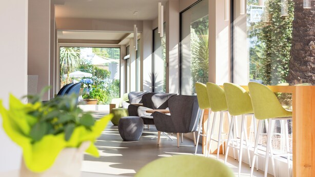 A modern interior with a sofa, chairs, and a dining area. - Hotel Brione Green Resort (Riva del Garda)