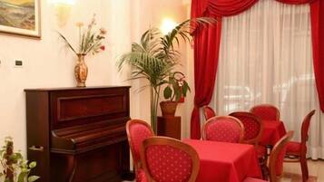 Un comedor con piano, manteles y sillas rojas.