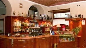 Un espace bar avec des meubles en bois, des étagères remplies de bouteilles et un sol carrelé.