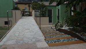 A stone pathway leading to a building with a green exterior.