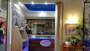 A hotel reception area with a wooden counter, a blue ceiling, and a sign that reads "Hotel Orchidias." - Hotel Orchidea (Turin)