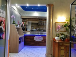 A hotel reception area with a wooden counter, a blue ceiling, and a sign that reads "Hotel Orchidias."