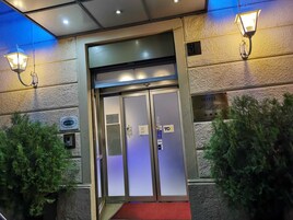 A hotel entrance with a glass door, a red carpet, and a sign indicating it is a hotel.