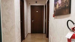 A hallway with wooden flooring, a fire extinguisher mounted on the wall, and a door at the end. - Hotel Orchidea (Turin)