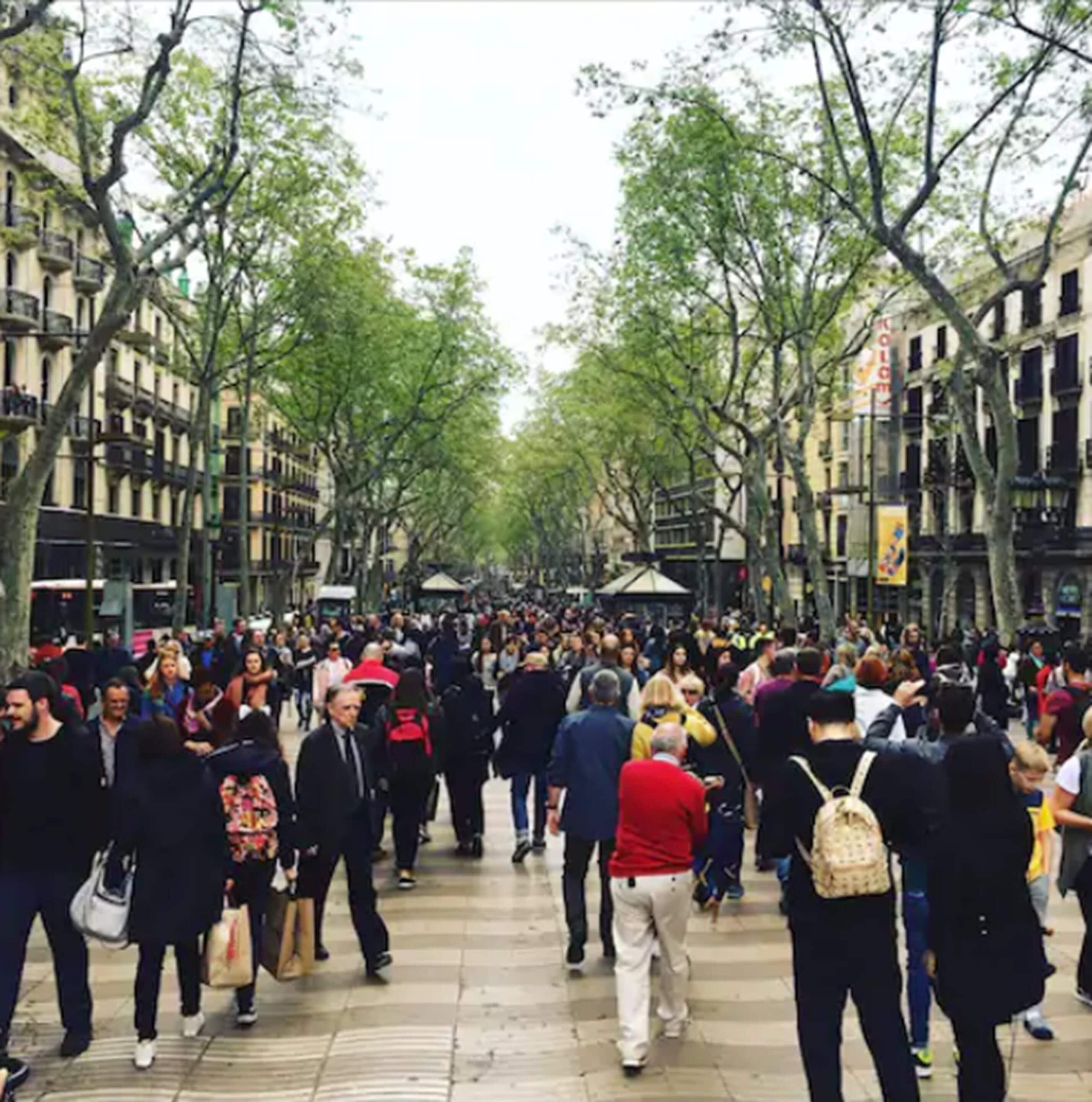 A crowded pedestrian street lined with trees and buildings.