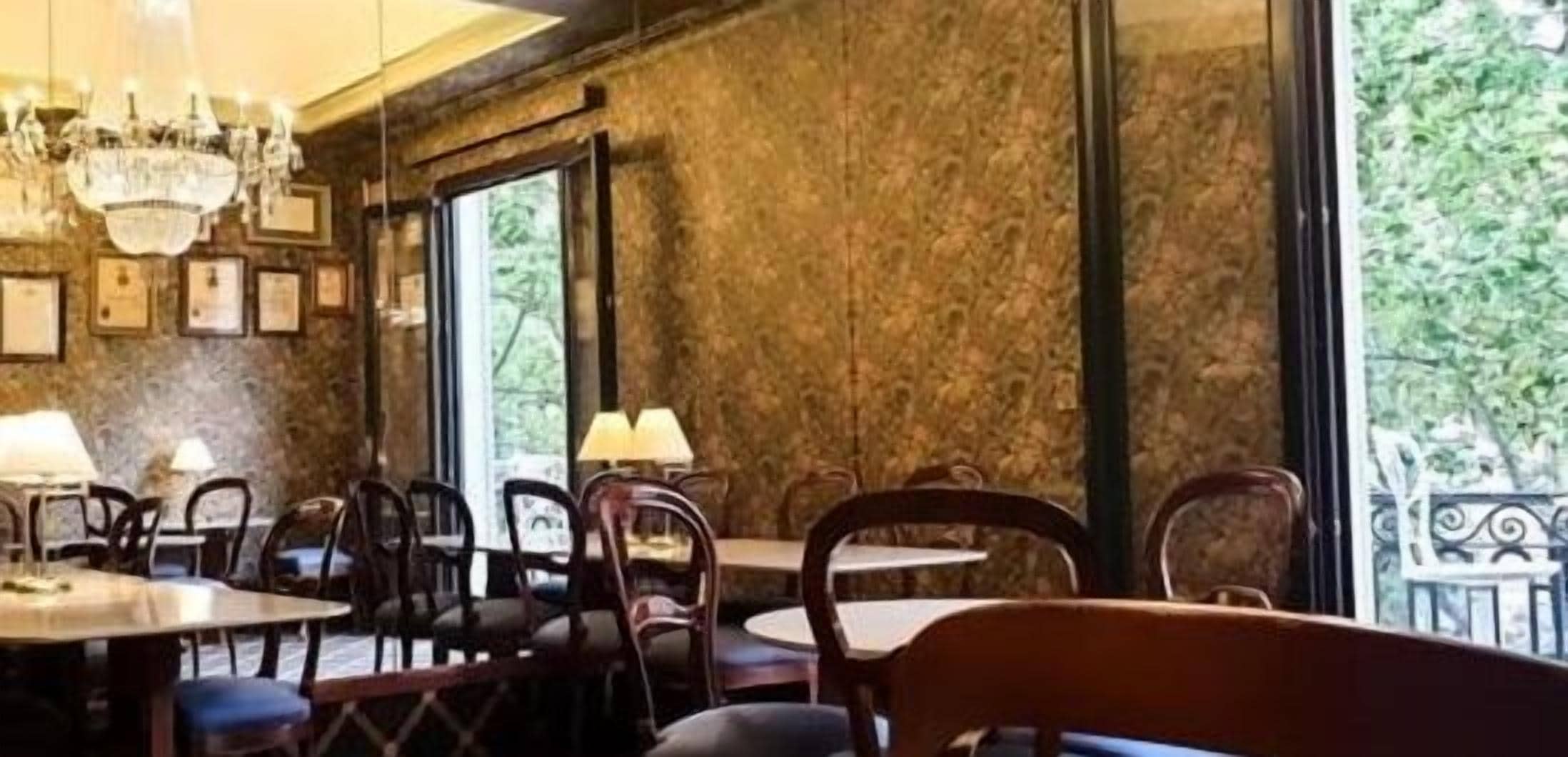 A restaurant interior with marble walls, wooden tables, and chairs.