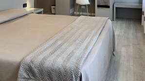Una habitación de hotel moderna con una cama grande, un escritorio, una silla, un armario y una araña.