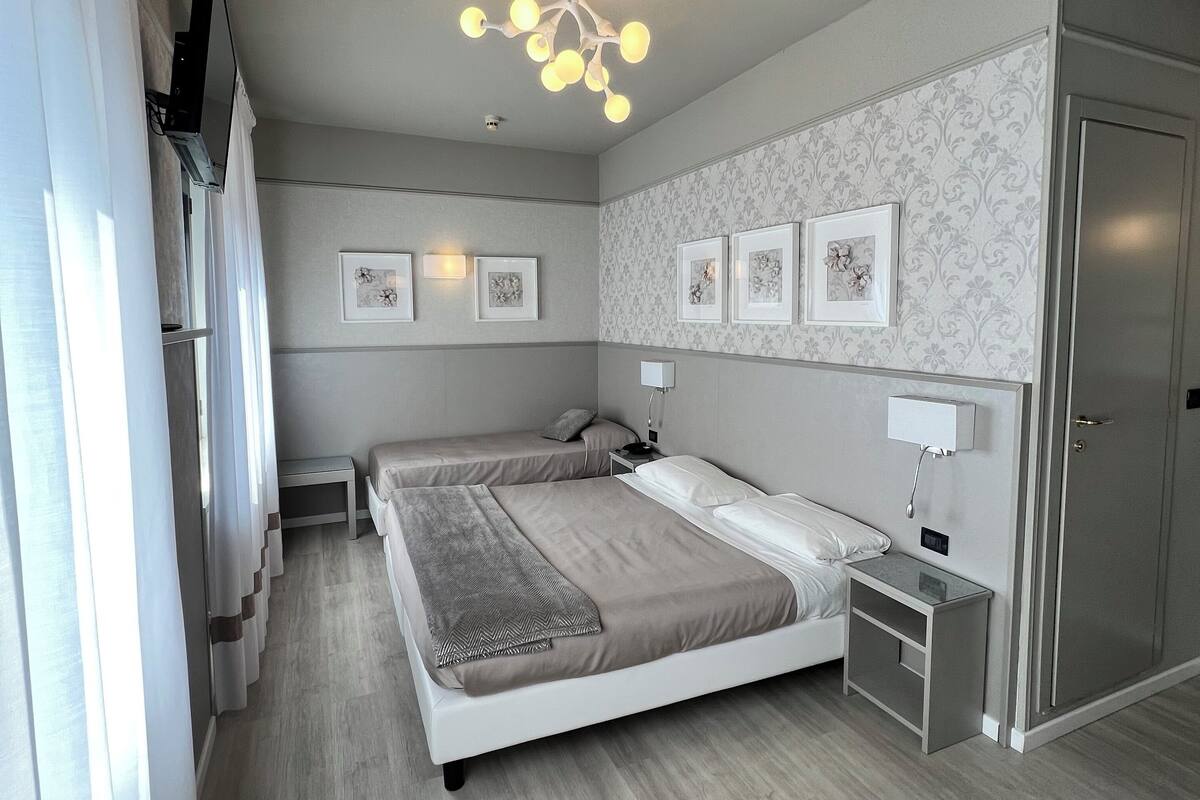 Ein modernes Schlafzimmer mit einem großen Bett, Nachttischen, einem Kleiderschrank und einer Deckenleuchte.