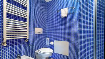 A bathroom with a blue tiled wall, a white sink, a toilet, and a towel rack.