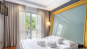 Ein Hotelzimmer mit einem großen Bett, weißen Leinen, einem großen Spiegel und Blick auf Grünflächen.