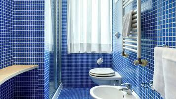 Ein Badezimmer mit blauen Fliesen, einer weißen Toilette, einem weißen Waschbecken und einem Handtuchhalter.