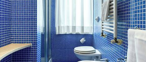 Un baño con paredes de azulejos azules, un inodoro blanco, un lavabo blanco y un perchero para toallas.
