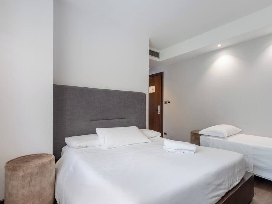 Habitación de hotel con dos camas individuales, un cabecero grande y una puerta de madera.