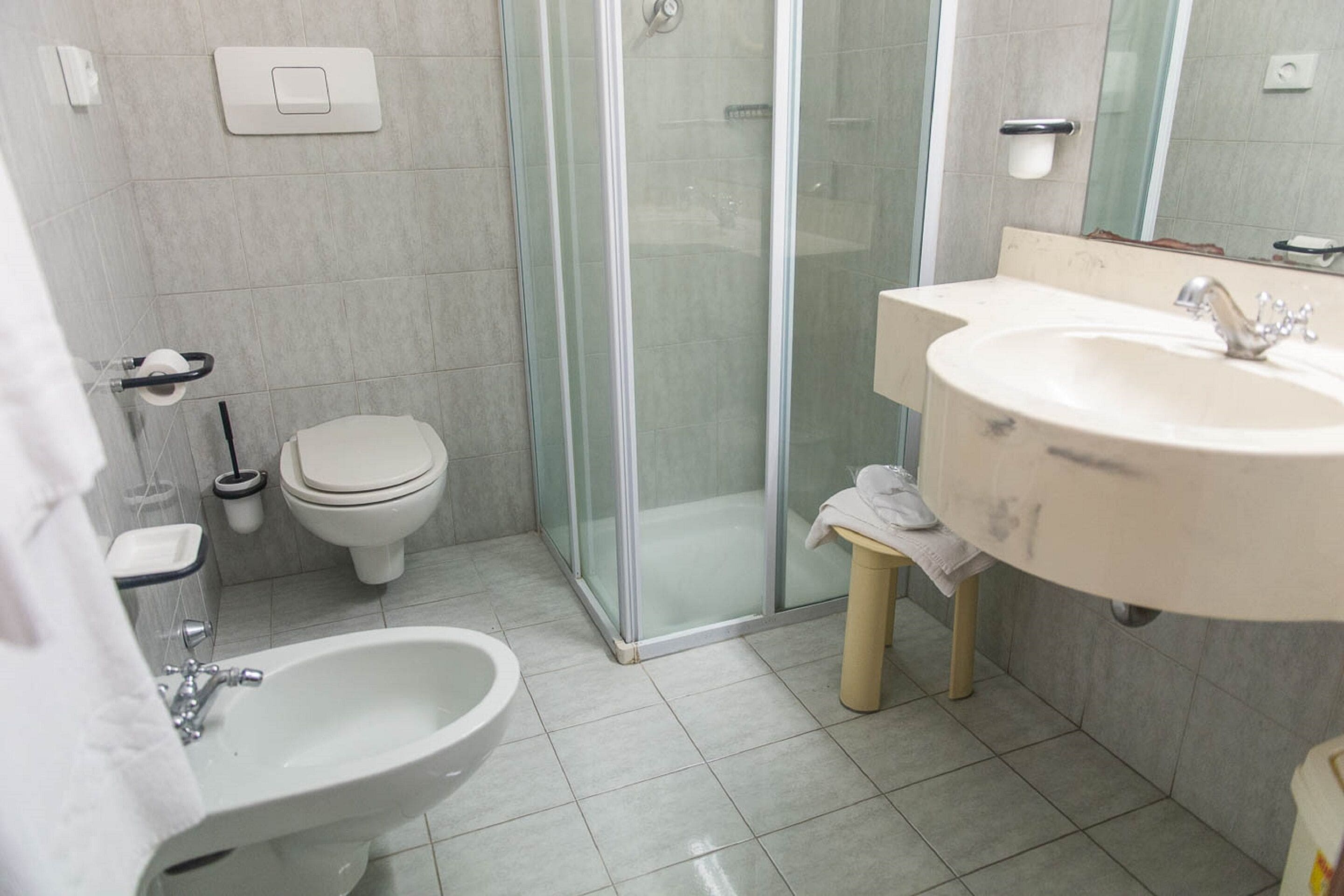 A modern bathroom with a glass-enclosed shower, a sink, a bidet, and a toilet.