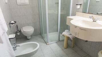 A modern bathroom with a glass-enclosed shower, a sink, a bidet, and a toilet.
