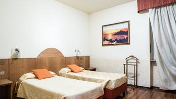 Ein Hotelzimmer mit zwei Betten, Holzboden, einem Wandbild und einem Vorhangfenster.