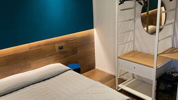 Un dormitorio con cama, armario con espejo y pared azul de acento.
