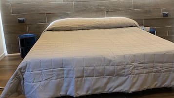 Une chambre à coucher moderne avec une tête de lit en bois, une couvre-lit matelassée et deux lampes suspendues.