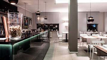 Un interno ristorante moderno con zona bar, posti a sedere e illuminazione a sospensione.