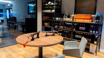 A modern bar area with a round wooden table, two chairs, and a wine rack filled with various bottles.