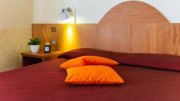A neatly made bed with a wooden headboard and two orange pillows.