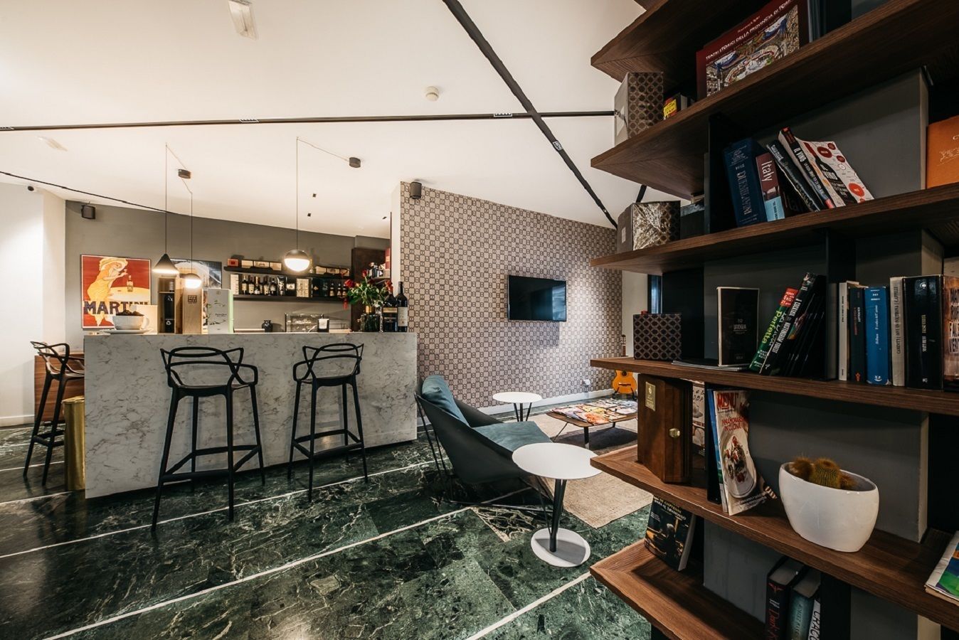 Una cocina moderna con barra, estantería y zona de estar con sofá y sillas.