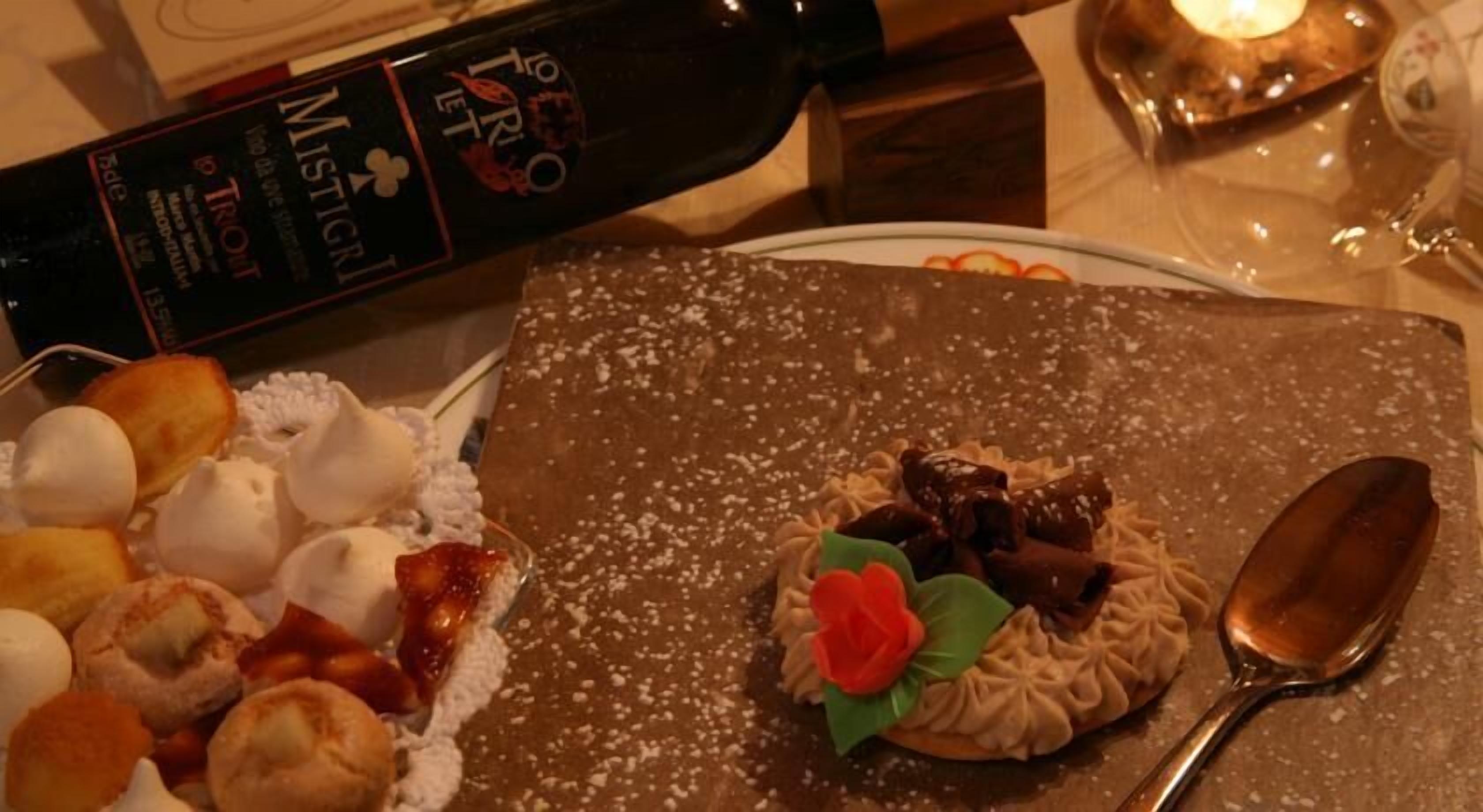 Um prato de sobremesas com doces variados e uma garrafa de vinho.