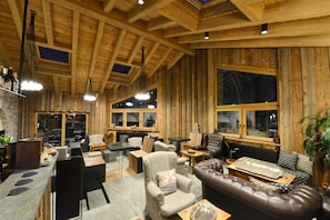 A cozy interior with a wooden ceiling, a fireplace, leather seating, and a bar area. - Maison Saint Jean (Courmayeur)