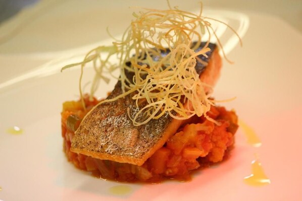 Un plato con un filete de pescado, puré y guarnición.