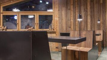 Un interior moderno con paredes de madera, un ventanal grande y una zona de comedor con mesa y sillas.